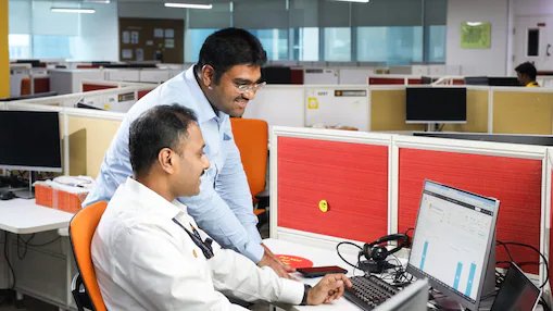 Two co-workers smiling and looking at laptop