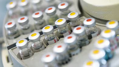 Rows of medicine vials sitting in a holder, some with red dots on the lid, and some with yellow dots on the lid