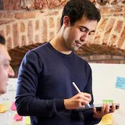 Male drawing on iPad with sticky notes on a whiteboard in the background.