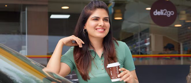 Woman holding a coffe cup near car